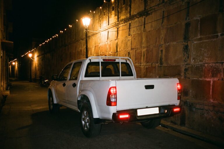 Double-cab pickup beside an old city wall at night
